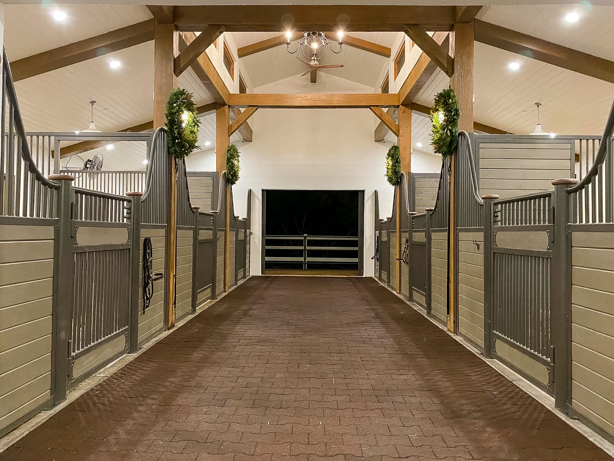 The inside of a horse barn with a brick walkway